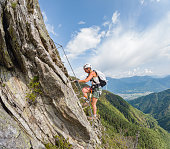 Woman climbs via ferrata ladder up rocky ridge