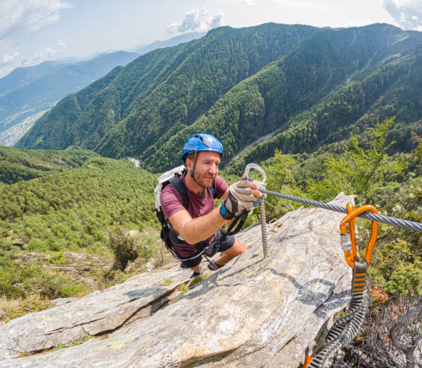 istock Man on alpine route climbs over steep rock wall 1494770352