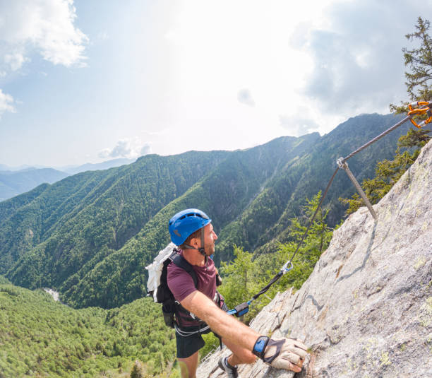 istock Man on alpine route climbs over steep rock wall 1494770372