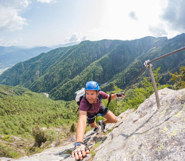 istock Man on alpine route climbs over steep rock wall 1494770397