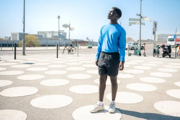portrait of young black sportsman standing on white circles at townsquare  in berlin