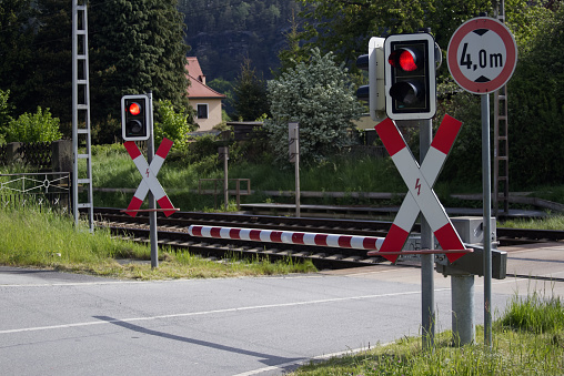 Red light of the railway crossing and lowered barrier blocking the passage