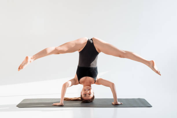 femme yogi avancée faisant la posture sur la tête avec les jambes en ficelle. - inversion yoga photos et images de collection
