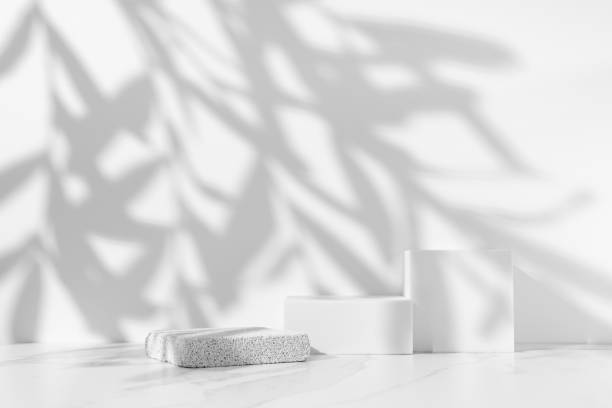 istock Minimal white scene for cosmetic product presentation made with empty white podiums on white background with leaves shadow. 1494775145