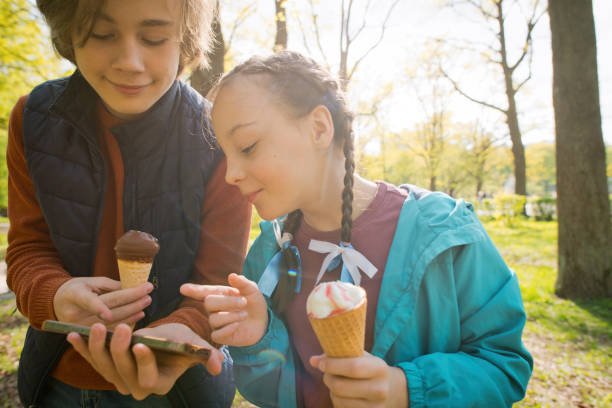 istock Children eating ice-cream and using smartphone in a summer park 1494775810