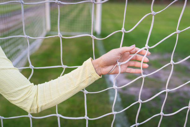 サッカー場、サッカーゴールの白いネットの近くに女の子が立っています。緑のフィールド。 - soccer field grass single line lawn ストックフォトと画像