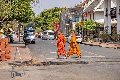 Luang Prabang, Laos - July 18, 2015: Luang Prabang, Laos - July 18, 2015: Morning alms in Luang Prabang, known as Tak Bat, is a serene Buddhist ritual. At sunrise, barefoot monks, draped in saffron robes, walk in silence through the streets. \n\nThis photo encapsulates the moment as visitors graciously offer food and beverages to the monks.