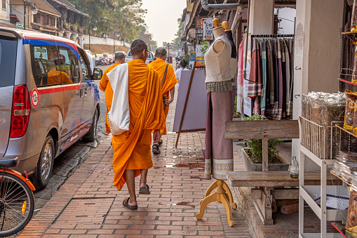 Luang Prabang, Laos - March 17th 2023: Monks in their orange robes are a common sight in the former capital of Laos