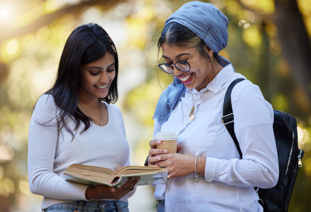 istock Happy, reading  or university friends in park on campus for learning, education or future goals together. Smile, Muslim or students relaxing with school books meeting to research or college knowledge 1494778539
