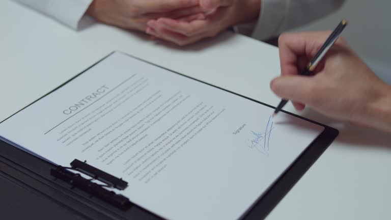 Closeup of young Asian businessman mentor corporate leader manager counselor communicate with businesswoman and sign a contract at office night. Businesspeople in workplace.