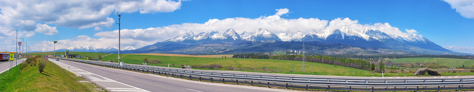 highway through the slovakian countryside, revealing a scenic view of the beautiful tatra mountains. the road leads through vast farmland, providing a beautiful backdrop for the journey