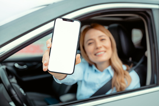 Woman Holding Phone With White Screen While Sitting Inside of Auto. Focus on Phone