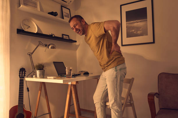 Man with hip, back, spine, hernia and sciatica pain at home. stock photo