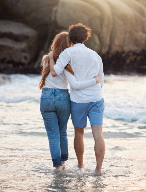 istock Back, hug and couple walking, beach and quality time on summer vacation, weekend break and romance. Romantic, man and woman embrace, love and happiness for holiday, journey and adventure together 1494786189