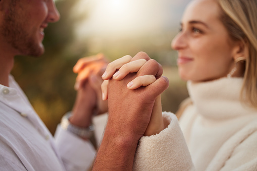 Love, smile and couple holding hands at sunset for bonding, quality time and romantic weekend. Dating, honeymoon and man and woman with palms together for trust, support and loving for valentines day