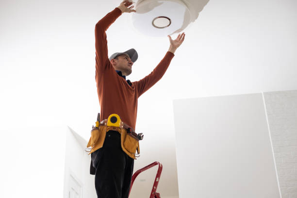 istock Electrician in uniform repairing ceiling lamp indoors 1494790568