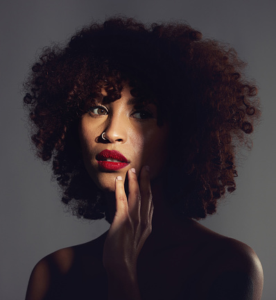 Shadow, red lipstick and makeup on black woman with beauty, afro or natural hair in studio. Face of aesthetic female model with a skin glow, shine and color on lips for art, power and facial skincare