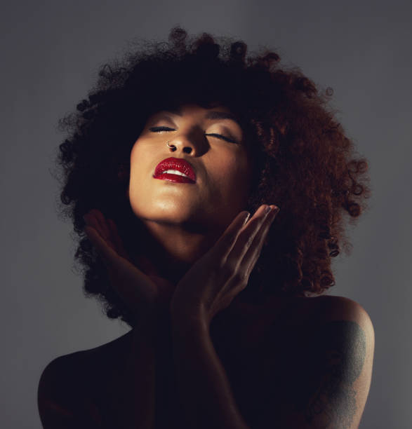 Black woman, shadow and makeup or red lipstick with beauty, afro or natural hair in studio. Face of aesthetic female model with hands to show skin glow, shine and color on lips for art and skincare mujer negra, sombra y maquillaje o labial rojo con belleza, afro o cabello natural en estudio. rostro de modelo femenino estético con manos para mostrar el brillo, brillo y color de la piel en los labios para el arte y el cuidado de la piel