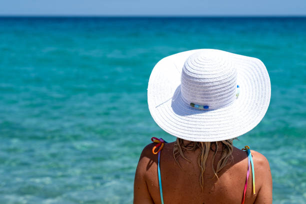 Woman with a hat on the beach.