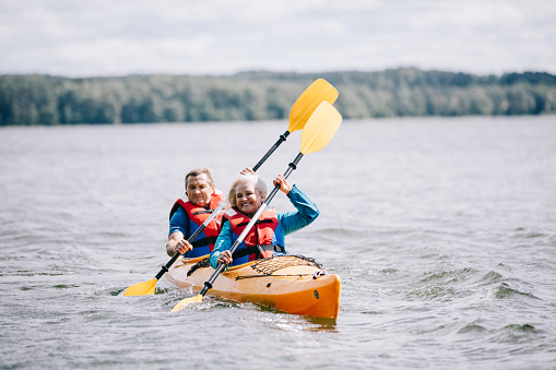 Happy senior active couple kayaking on lake enjoying time together
