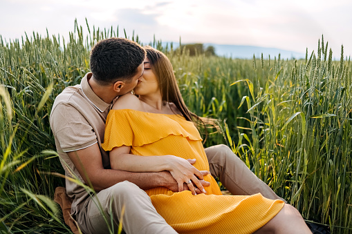 Happy pregnant couple resting in nature and enjoying