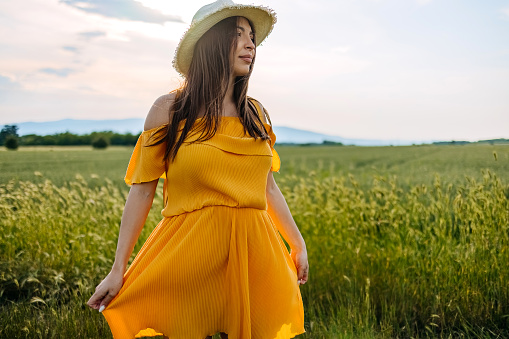 Pregnant woman standing alone in a field and enjoying nature