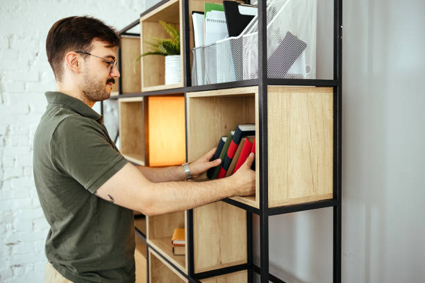 istock Man searching for book in shelves at home 1494815263