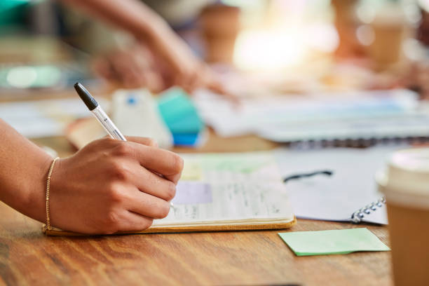istock Hands, writing and book for business schedule, planning or brainstorming notes on office desk. Hand in project plan taking note for corporate or company strategy in reminder, idea or tasks on table 1494818579