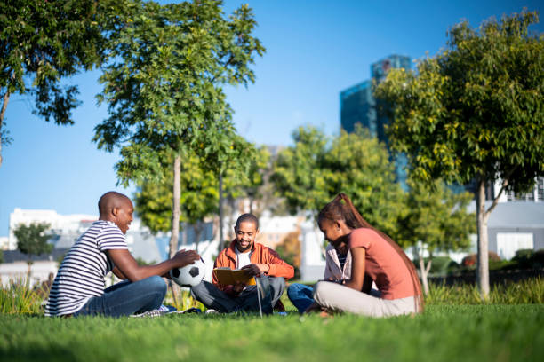 Group of friends sitting & relaxing on the lawn in the park on a sunny day