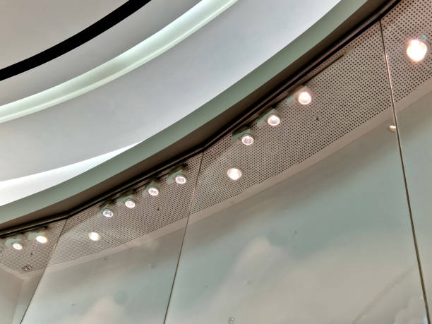 istock shop window backlighting. large-scale glass windows and plasterboard soffit ceiling in the shape of a arch. spot lamps near the ceiling shine on displayed fashion items for sale discount, shopkeeper 1494825160