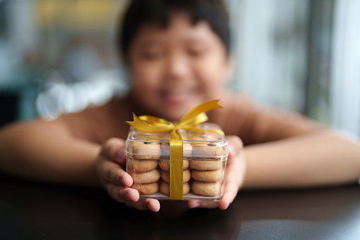 Happy Asian Boy Hands Holding A Cookies Box With Golden Ribbon, Holiday Concept
