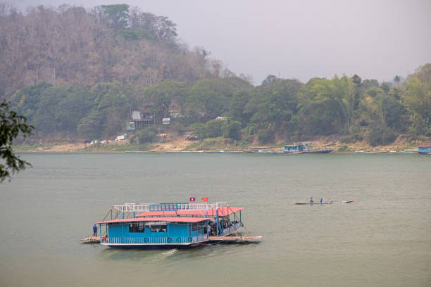 Mekong River, Luang Prabang, Laos - March 16th 2023: Car ferry crossing the Mekong river on a hazy day in the former capital of Laos