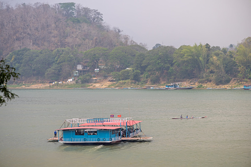 Mekong River, Luang Prabang, Laos - March 16th 2023: Car ferry crossing the Mekong river on a hazy day in the former capital of Laos