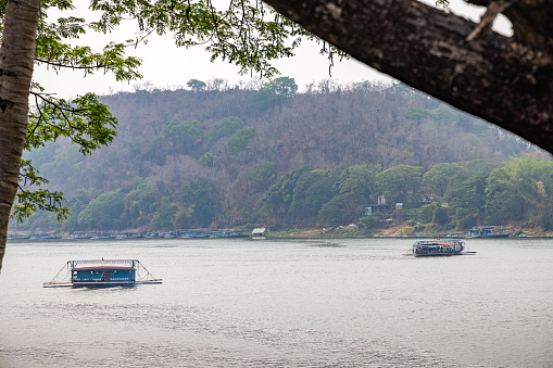 Mekong River, Luang Prabang, Laos - March 14th 2023: Car ferries crossing the Mekong river on a hazy day in the former capital of Laos