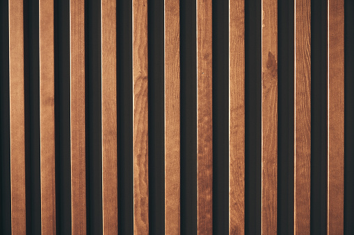 Wall decor with wooden vertical bars. A modern way of decorating walls in rooms, apartments and offices. Wall with wood paneling on black with copy space. High quality photo