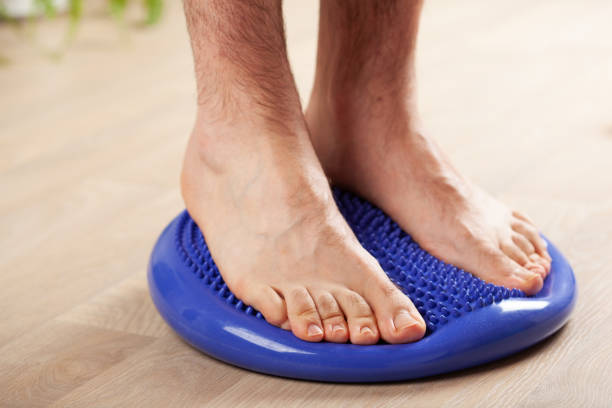 man doing flatfoot correction gymnastic exercise balancing on massage cushion at home
