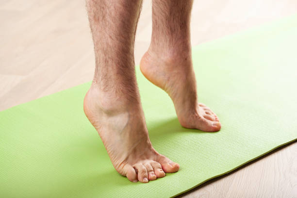 man doing flatfoot correction gymnastic exercise standing on toes at home man doing flatfoot correction gymnastic exercise standing on toes at home pes planus stock pictures, royalty-free photos & images