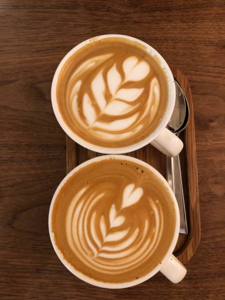 istock Two cappuccino coffee cups with the heart shape closeup top view, rustic wooden background. 1494832419