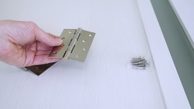 Worker checks and shows the work of the door hinges.