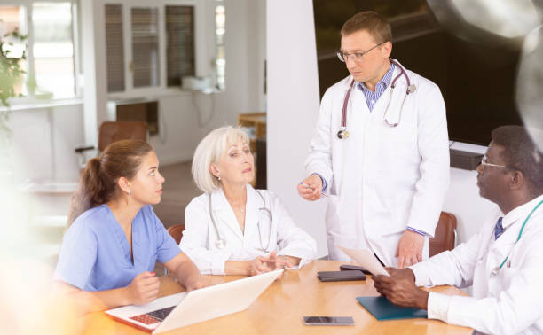 istock Middle-aged doctor talking to his colleagues sitting around table 1494834088