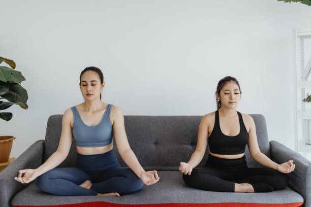 istock women doing yoga exercise on sofa at home 1494836171