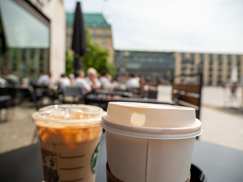 Paper cup with coffee on the background of a blurred city. Close-up glass of coffee.