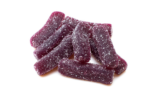 Pile of purple sugary jelly candies isolated on white background. Gummy worms treat