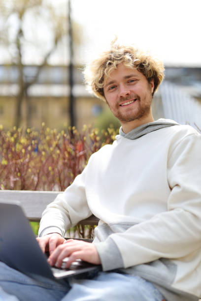 istock A curly-haired man works on a park bench. 1494842822