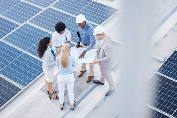 istock Solar energy, business people or engineering team with blueprint on roof building grid technology for sustainability. Collaboration, top or employees talking or planning development project strategy 1494843996