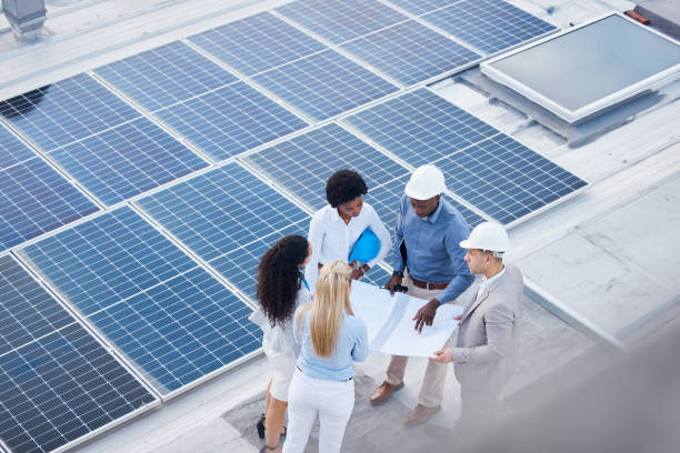 istock Solar energy, teamwork or engineering designers with blueprint on roof building grid technology for innovation. Collaboration, top view or business people talking or planning a development project 1494844004