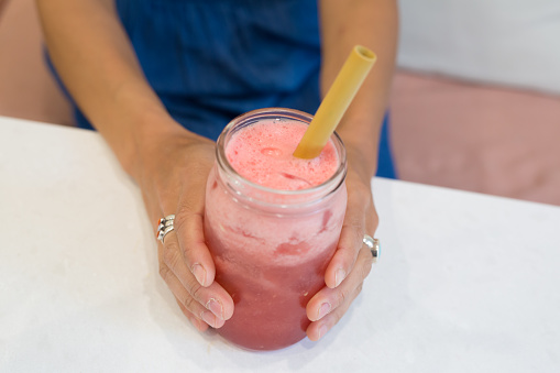 Woman holds a watermelon mixed drink made with watermelon, soda, coconut water and mint