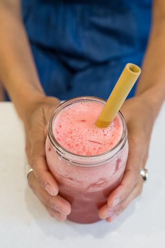 Woman's hands holding a watermelon drink made with watermelon, coconut water, soda and mint