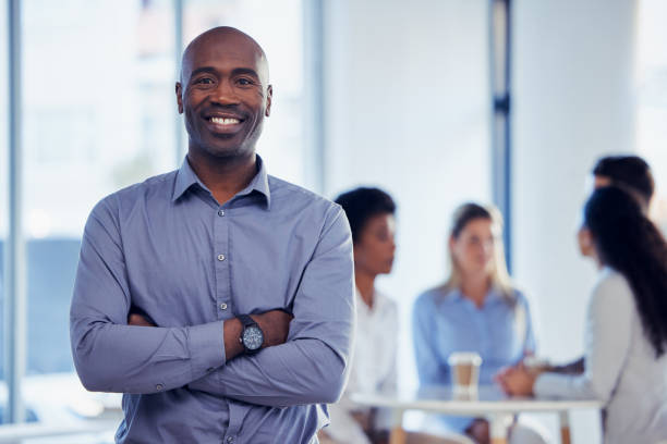 uomo d'affari, manager aziendale e ritratto di un impiegato di leadership d'ufficio con un sorriso. ceo orgoglioso, background sfocato e successo di un lavoratore di gestione con motivazione dalla collaborazione del team - business ceo building activity business person foto e immagini stock