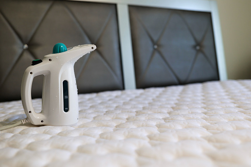 A steamer sitting on top of a mattress to sanitize a bed